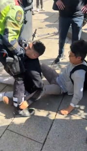 Police officer arresting a man on the ground.