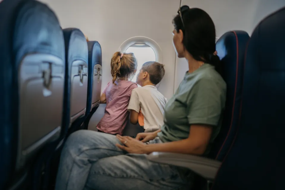 Mother and two children looking out airplane window.