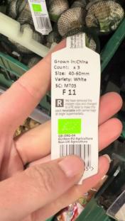 Close-up of a product label for 3 white garlic bulbs, grown in China.