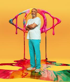 Daley Thompson standing in front of a large, colorful eye illustration.