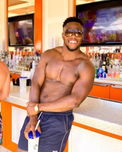 Shirtless man smiling at a bar.