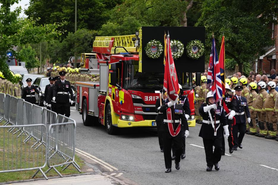 Firefighters and mourners at a funeral procession.