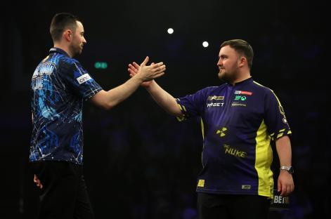 Luke Humphries and Luke Littler shaking hands before a darts match.