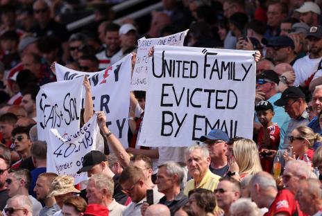 Manchester United fans holding signs protesting recent club changes.