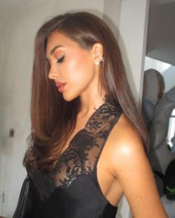 Woman with long brown hair wearing a black lace top.