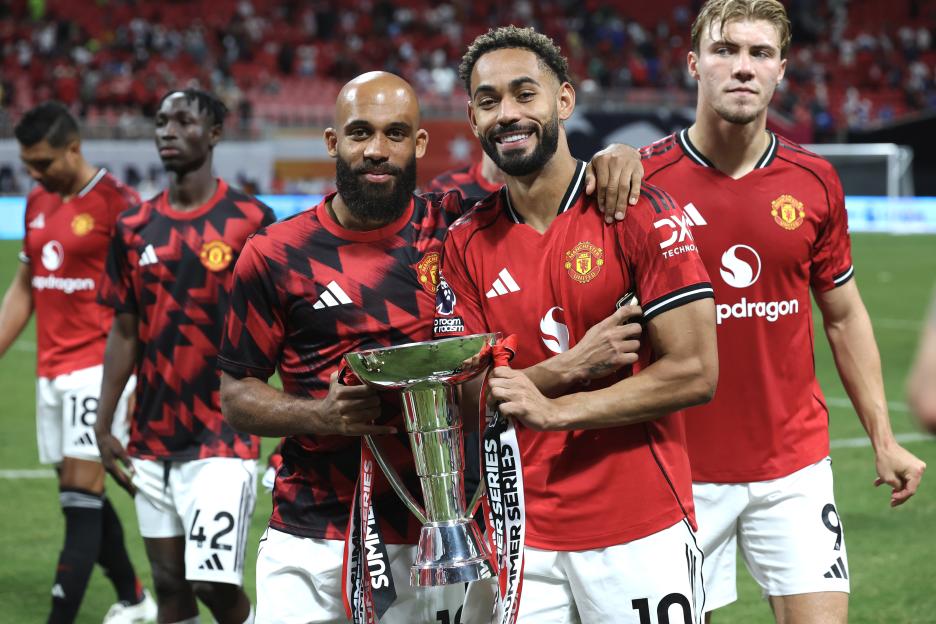 Manchester United players celebrating with a trophy.