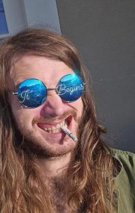 Man with long hair and round sunglasses that say