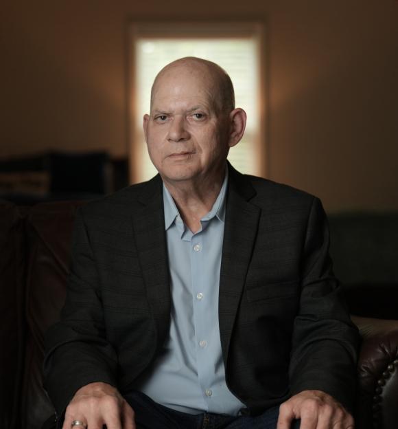 a man in a suit and blue shirt is sitting on a couch