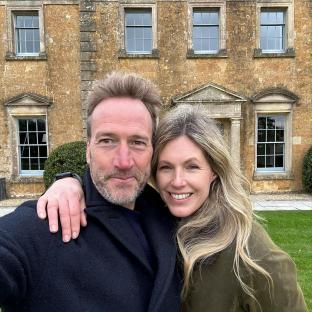 Ben Fogle and his wife Marina in front of a large house.