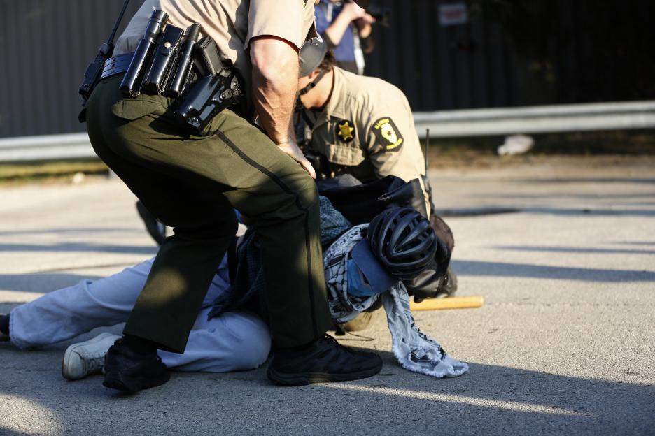 Law enforcement officers detaining a man on the ground.