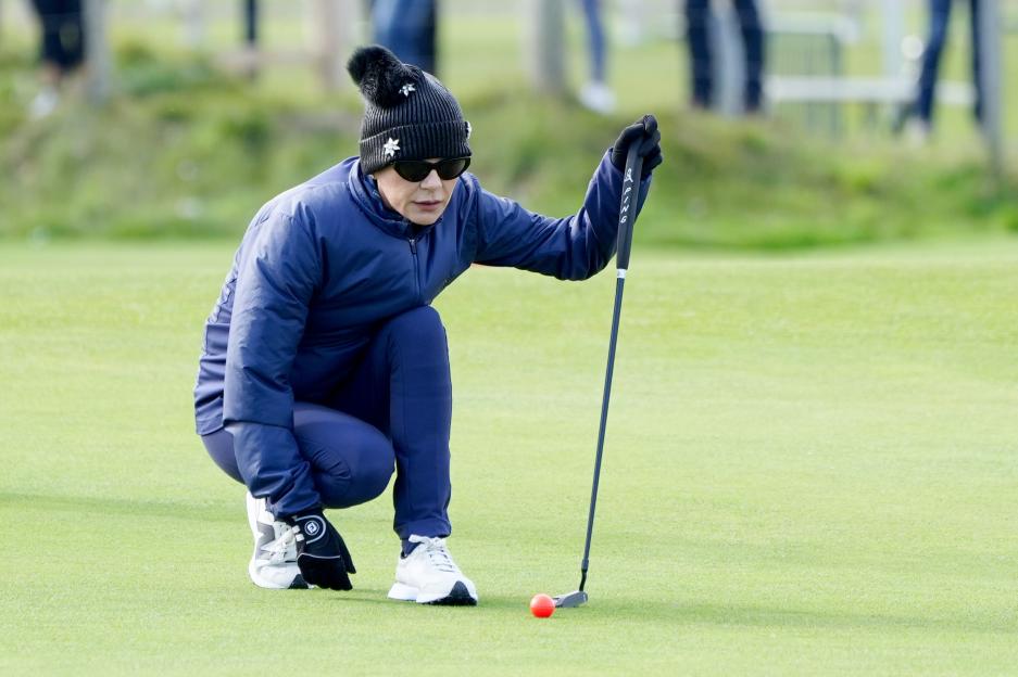 Catherine Zeta-Jones lining up a golf putt.