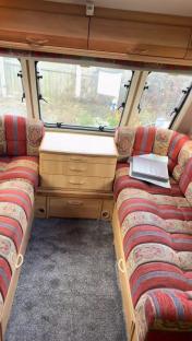 Interior of a caravan with red striped seating and wooden cabinetry.