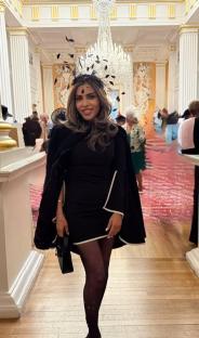 Woman in black dress and feather headpiece at an event.