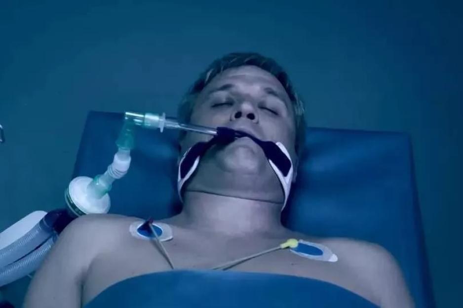 Joe Tate sedated in a hospital bed.