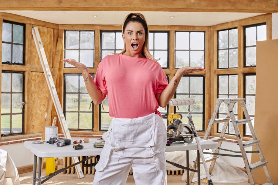 Katie Price in paint-splattered overalls, surprised expression, amid home renovation.