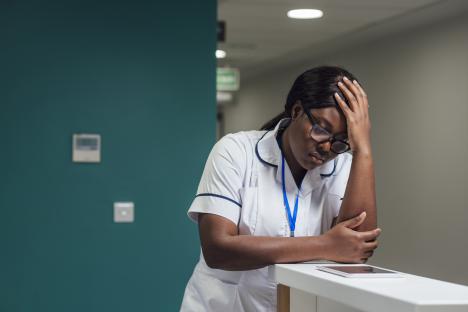 A young student nurse looking concerned while leaning on a desk.