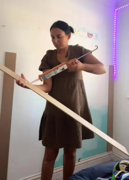 Woman applying adhesive to wood paneling.