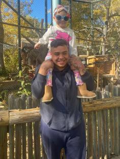 A man carrying a toddler on his shoulders at a zoo.