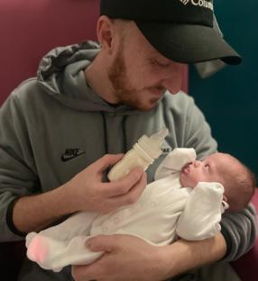 Man bottle-feeding newborn baby.