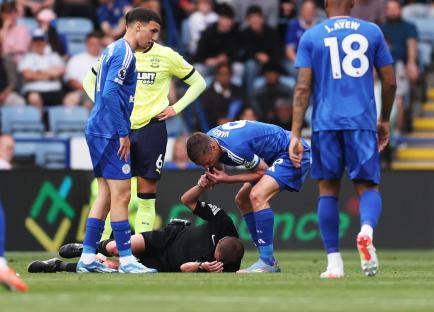 Leicester City player Jamie Vardy attends to an injured referee during a soccer match.