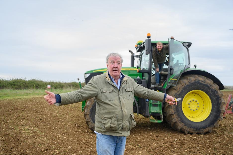 Jeremy Clarkson and Kaleb Cooper standing in a field with a tractor.