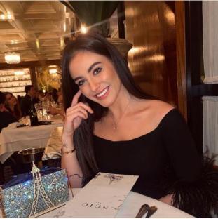 Woman in black off-the-shoulder top at restaurant.