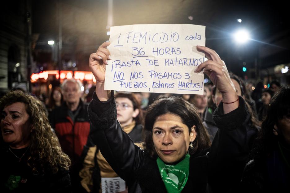 A woman holding a sign that reads "1 femicide every 36 hours. Stop killing us! We are not 3 towns, we are fed up!" at a protest.