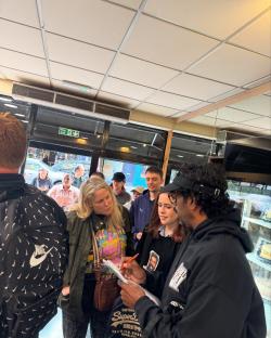 Romesh Ranganathan signing autographs at a bakery.
