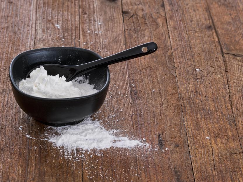 Cornflour in a black bowl with a spoon.
