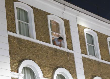 A man looking out a window of a brick building.