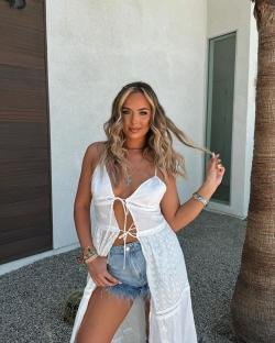 Woman in white eyelet dress and denim shorts.