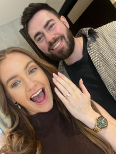 A happy couple, the woman showing off her engagement ring.