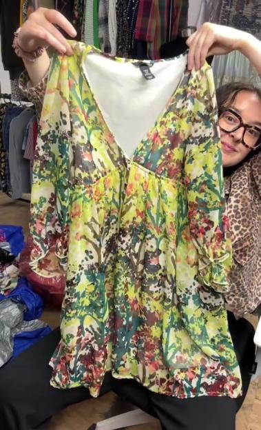 Woman holding up a floral blouse.