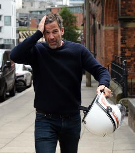 Gethin Jones carrying a motorcycle helmet.