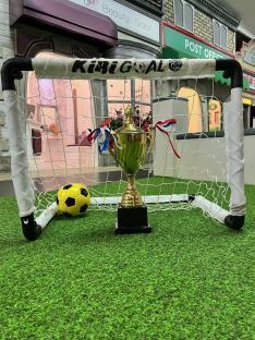 Soccer ball and trophy in front of a soccer goal in a children's play village.