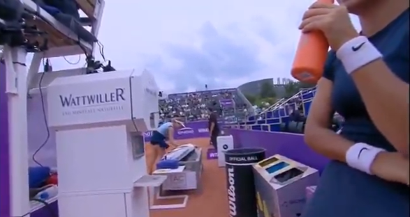 Tennis player drinking from a bottle during a match.