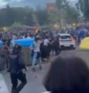 Large group of people clashing with police in a street.
