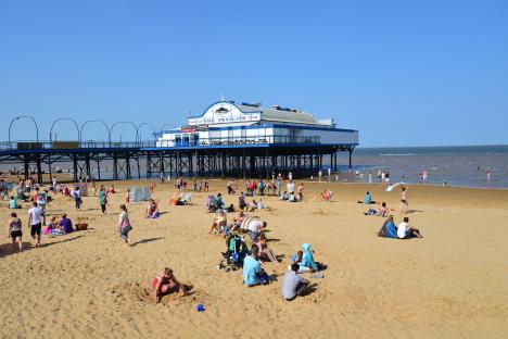 Cleethorpes beach with pier and pavilion, many people enjoying the sunny day.