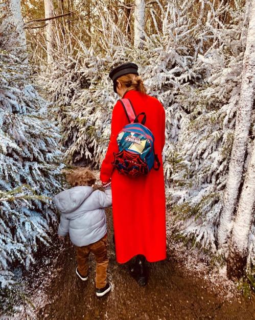 Woman and child walking through a snow-covered forest.