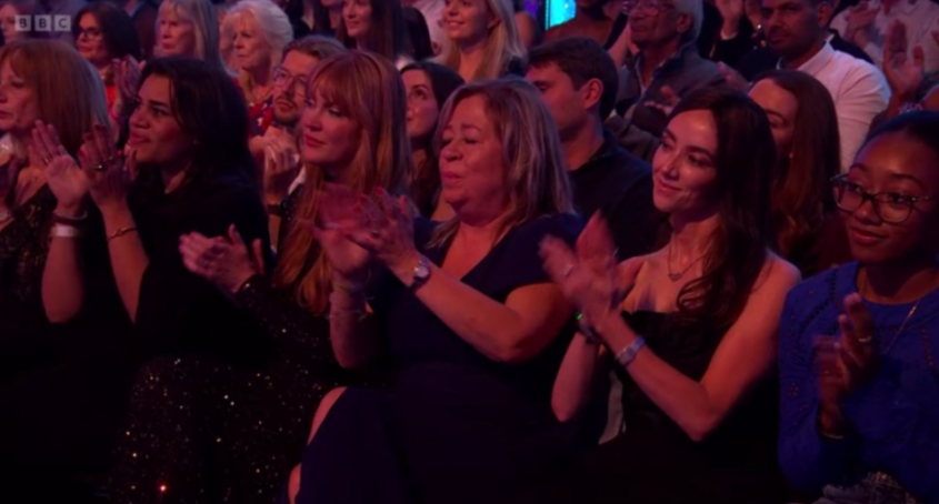 A diverse group of audience members, mostly women, clapping.