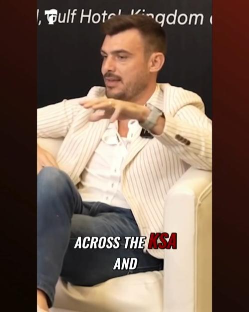 Man in striped blazer sitting and speaking.