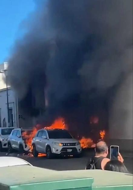 Thick black smoke billowing from the supermarket as flames engulf the shop entrance.