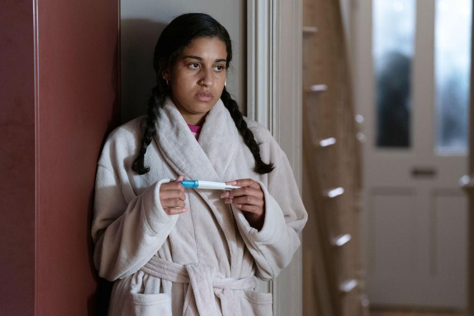 Woman in bathrobe looking at pregnancy test.