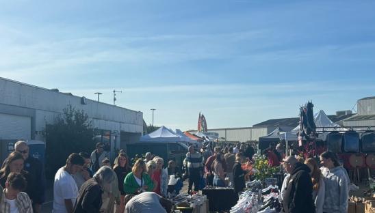 Crowded outdoor market with many vendors and shoppers.