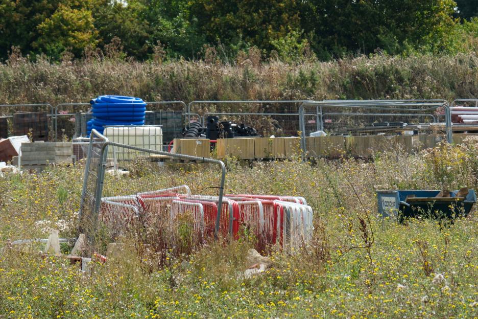 Abandoned construction site overgrown with weeds.