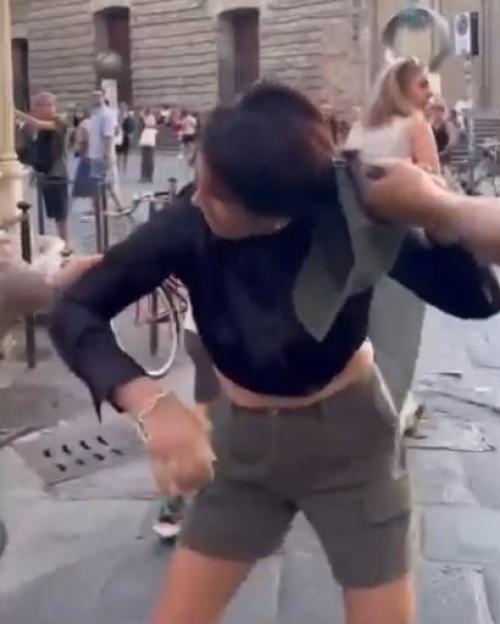Woman being grabbed by the hair by a man in a public street.