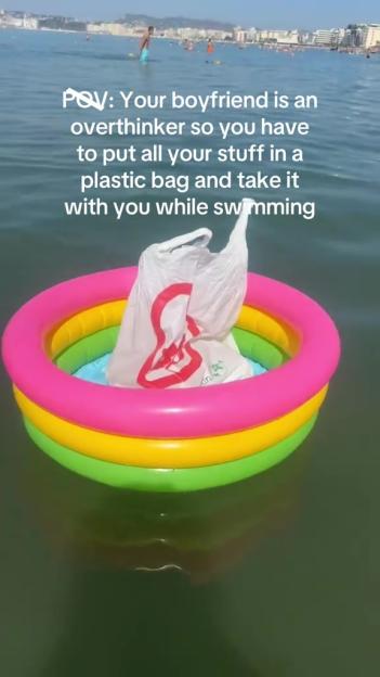 Plastic bag of belongings floating in a colorful inflatable ring in the ocean.