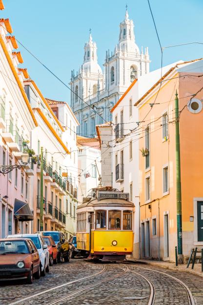 Yellow tram on cobblestone street in Lisbon, Portugal.