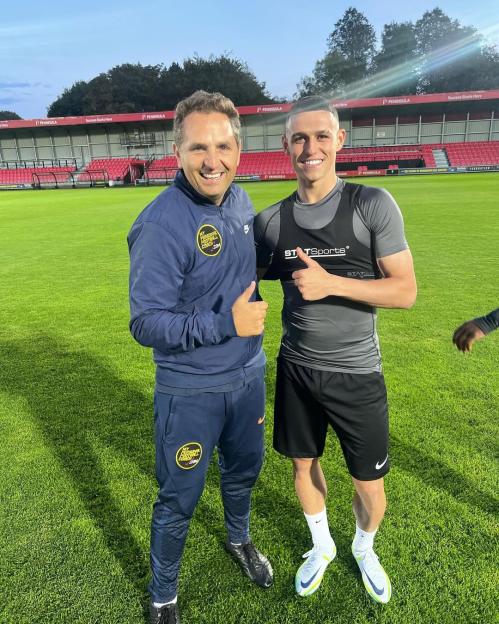 Two men giving thumbs up on a soccer field.