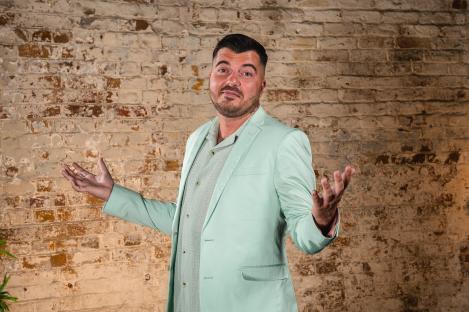 Luke Worley in a light green suit, gesturing with his hands.